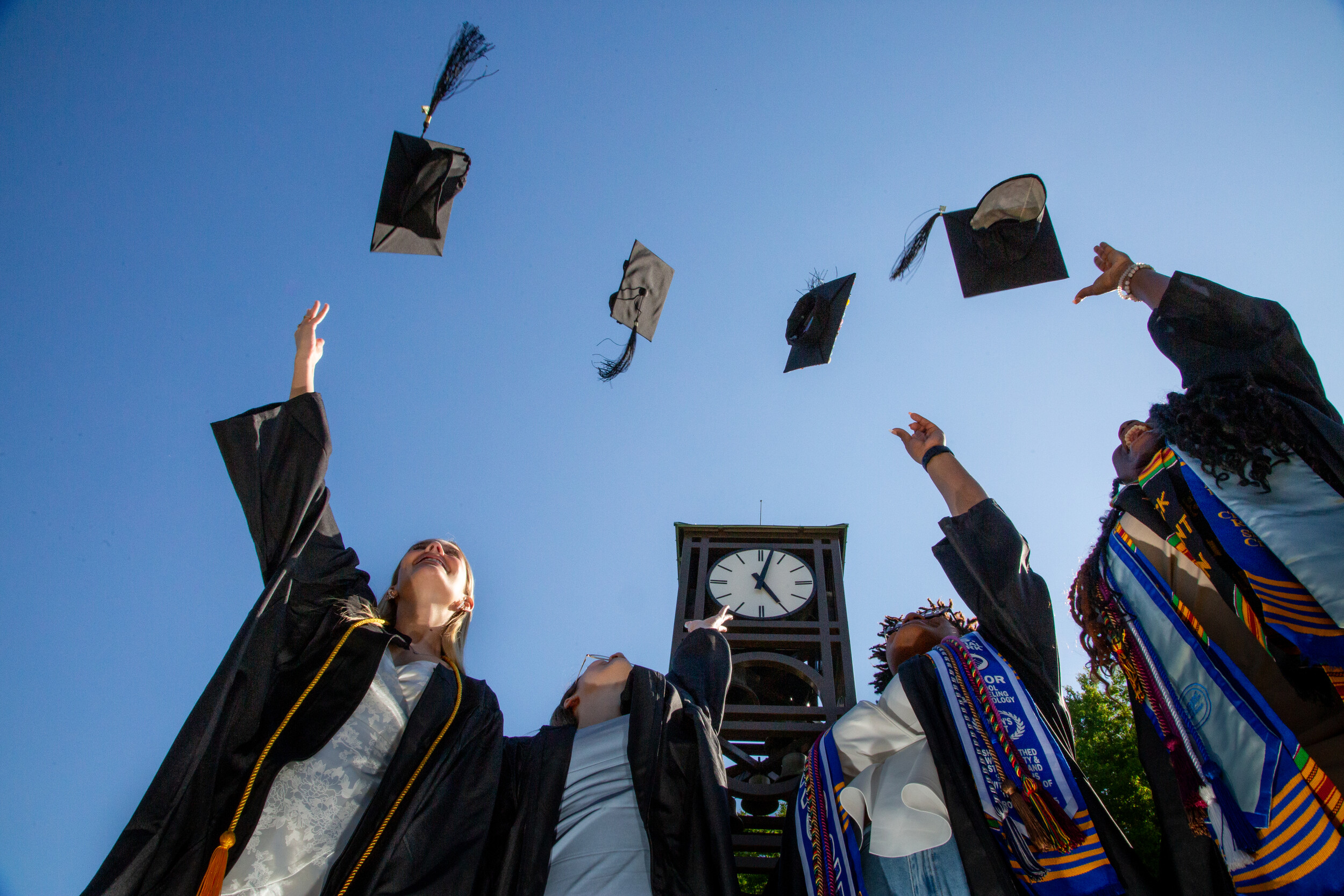 Graduates of SUNY Fredonia tossing their mortar boards into the air. 