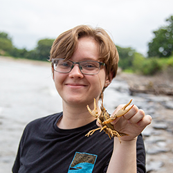 smiling student holding a crustacean at the Lake Erie Shore