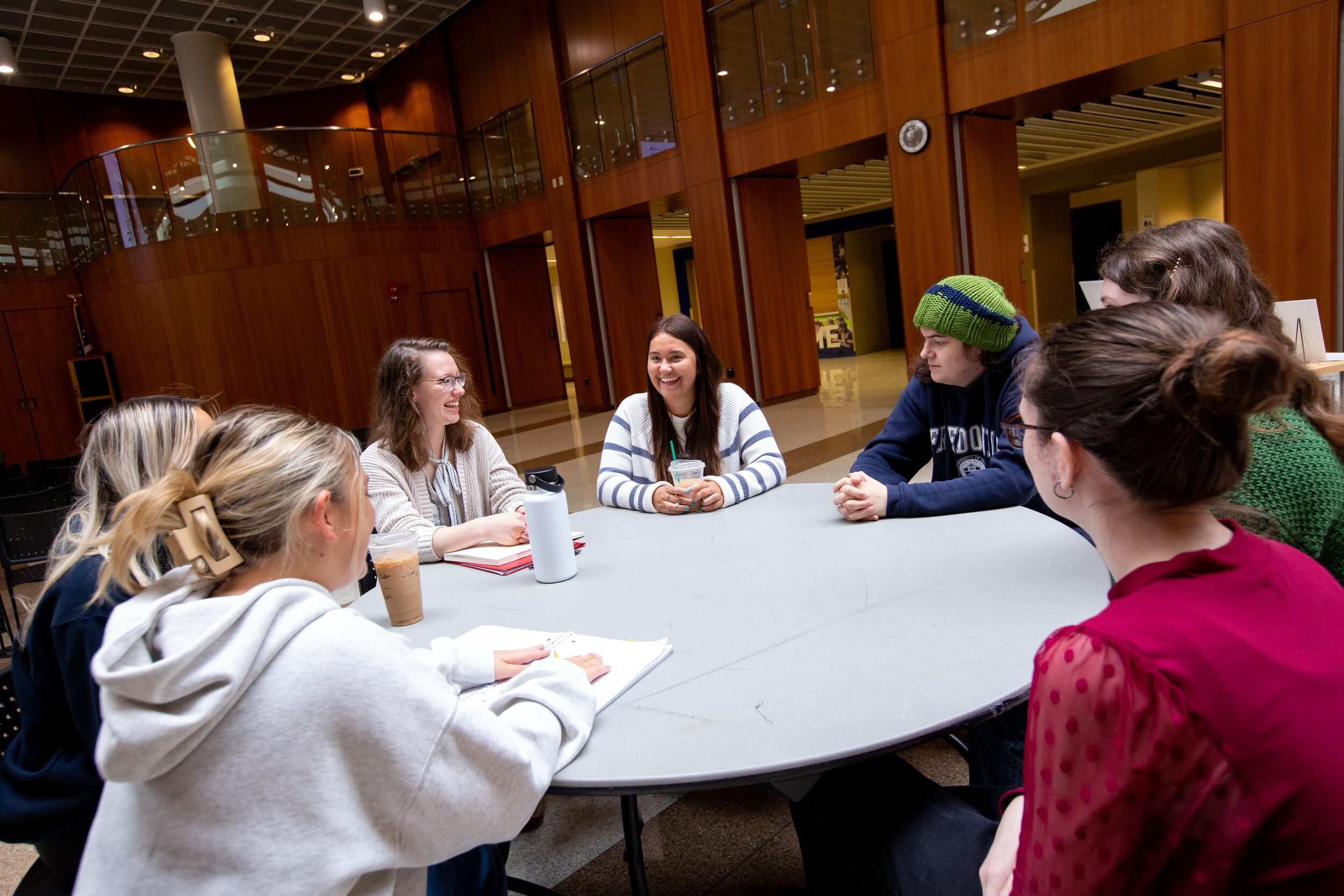 A group of students sits around a table talking and laughing.