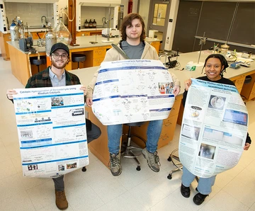 three students holding their research posters