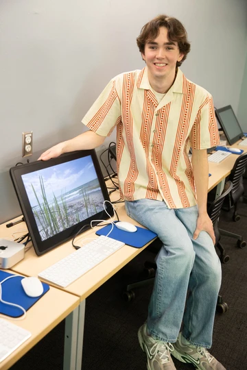 James Gibbons, in a Michael C. Rockefeller Arts Center animation lab, with his a scene from his documentary displayed on a monitor.