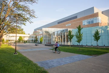 student bike riding by science center. The molecular genetics program at Fredonia trains the next generation of scientists.