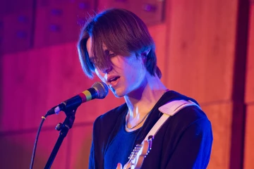 Student playing guitar and singing during battle of the bands