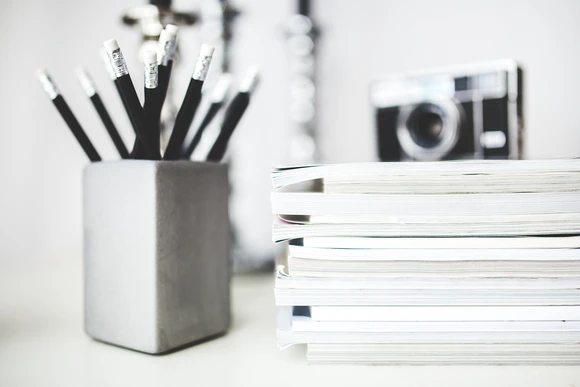 pens in cup by papers. Earning an English degree prepares students for a variety of careers in the arts and humanities.  