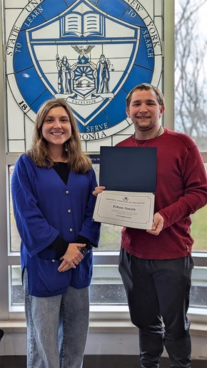 Ethan Smith holding his award certificate, joined by Chautauqua Hall Residence Director Donna Good