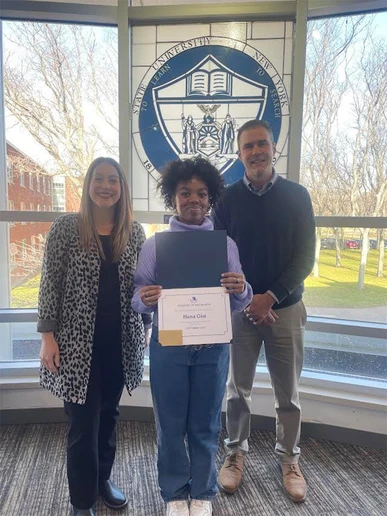 photo of Hana Gist holding certificate, with Campus Life staff