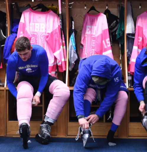 photo of skaters in front of pink jerseys lacing skates