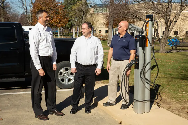 Staff members next to EV charging station