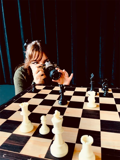 woman with a camera taking a photo of a chessboard