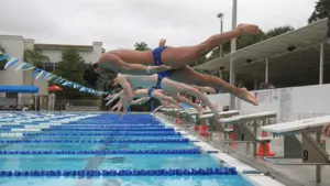 swimmers diving into pool