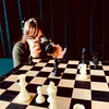 woman with a camera taking a photo of a chessboard